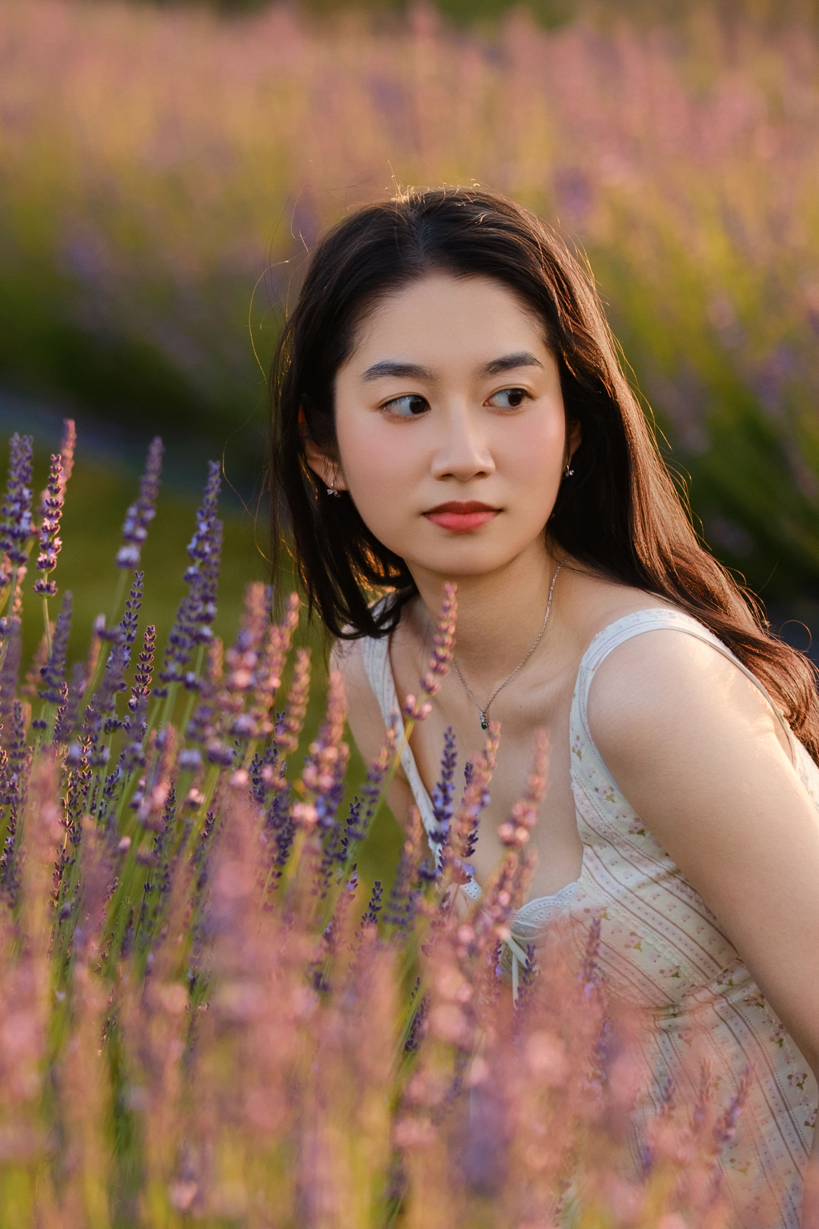 Close portrait of a woman surrounded by tall lavender stems.